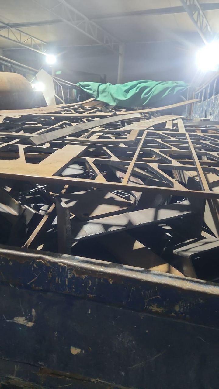 Laser-cut steel sheet offcuts stacked in a skip inside a workshop