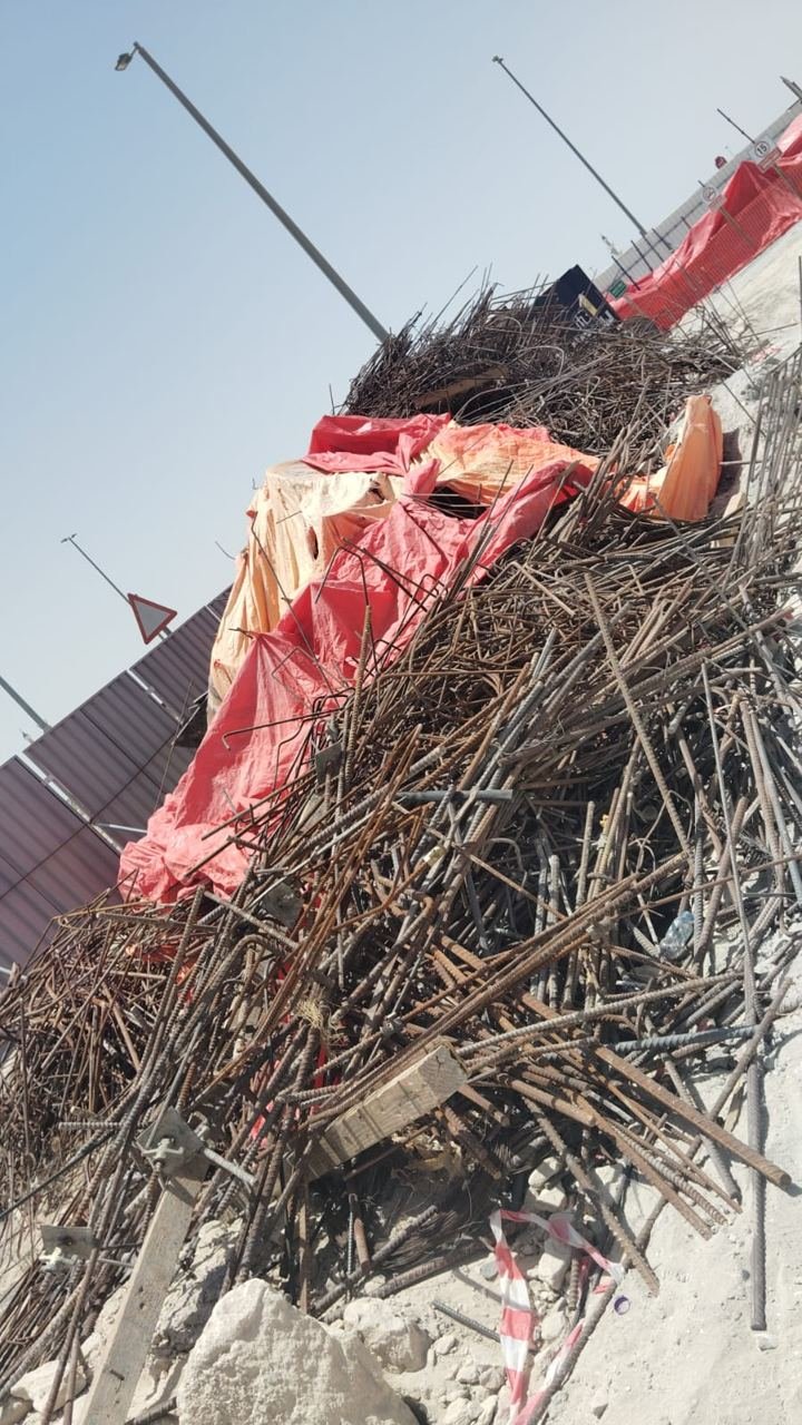 Large pile of used rebar and metal offcuts covered with a tarpaulin at a road construction site